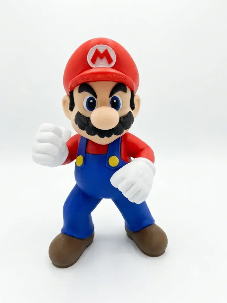 Statuetta Super Mario in PLA stampato 3D in posa da combattimento, cappello rosso con M bianca, salopette blu, guanti bianchi e scarpe marroni