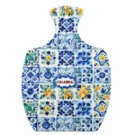 Tagliere a paletta con mosaico di piastrelle floreali blu, verdi e arancio e scritta Calabria al centro in lettere rosse.