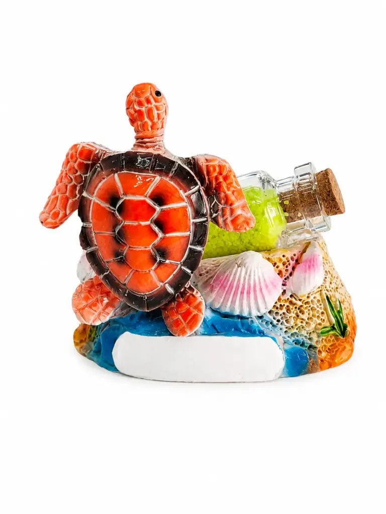 Statuetta tartaruga marina arancione in resina su base azzurra con bottiglia vetro e conchiglie