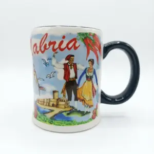 Tazza ceramica bianca Calabria con coppia in costume regionale, castello costiero e peperoncini rossi. Manico verde scuro, profilo ondulato.