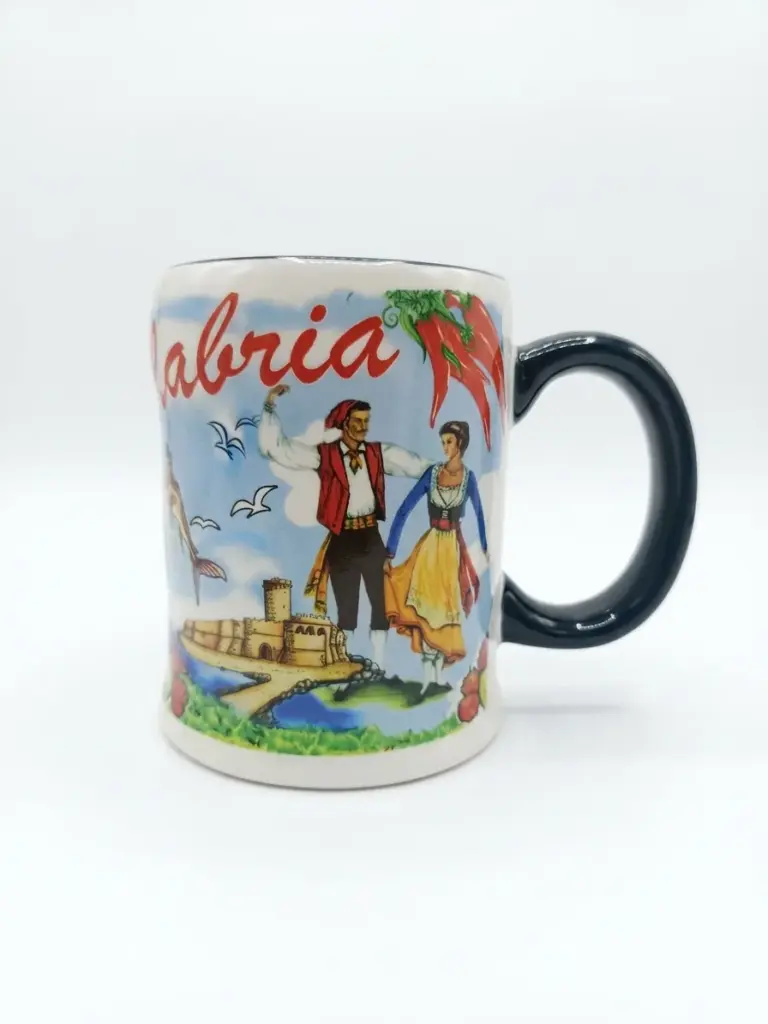 Tazza ceramica bianca Calabria con coppia in costume regionale, castello costiero e peperoncini rossi. Manico verde scuro, profilo ondulato.
