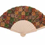 Ventaglio pieghevole con stecche in legno chiaro e tessuto patchwork in rosso, verde, blu e arancio con motivi geometrici e floreali